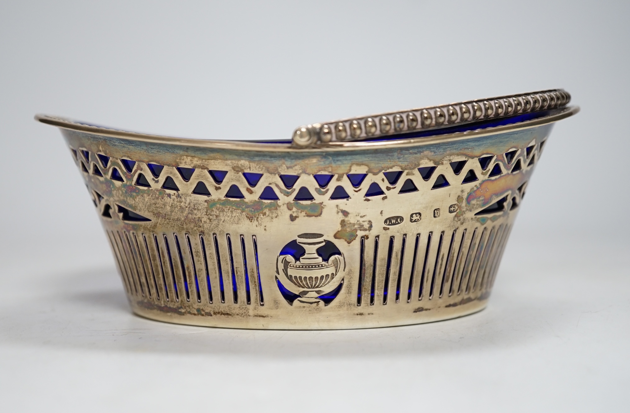 A late Victorian silver oval sugar basket, J.W. Caldicott, Birmingham, 1895, with blue glass liner, length 16.3cm.